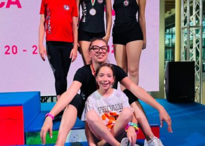 Ginnaste della ritmica festeggiano sul podio a Rimini 2025 con bandiera della società